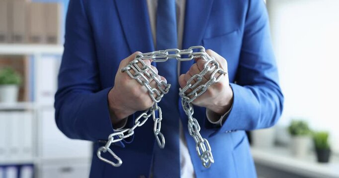 Businessman in suit wraps around hand chain in office symbolizing financial constraints. Business challenges and economic pressures in corporate world