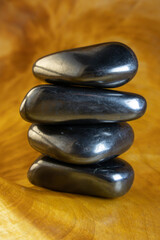 Four black stones stacked on top of each other. The stones are on a wooden surface