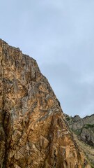 Rugged cliffs tower solemnly against an overcast sky, evoking adventure on Earth Day and the whimsical spirit of Geologist Day