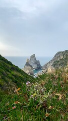 Craggy, mystical sea stacks emerge from verdant cliffs, evoking nature's drama perfect for Earth Day or Biodiversity Celebration