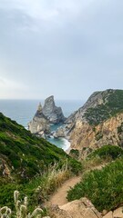Rugged cliffs cradle mystic sea stacks on a serene coastal trail, perfect for Midsummer meditation or Autumn Equinox reflection
