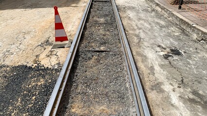 Dusty railway track under construction, evocative of steampunk nostalgia, Industrial Heritage Day, caution cone signaling unexpected journeys