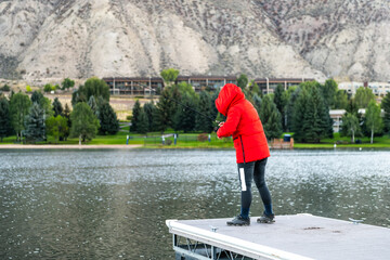 Nottingham lake park dock in Avon, Colorado cold morning with woman in winter coat on fishing pier sunrise in small mountain village ski town city