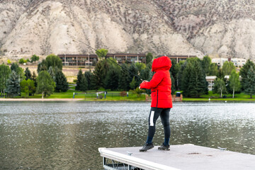 Nottingham lake park in Avon, Colorado cold morning with unrecognizable woman in red winter coat on fishing pier sunrise in small cold mountain town