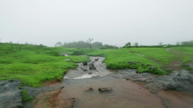 4K shot of a small water stream as seen on the way towards Naneghat Reverse waterfall in Maharashtra, India. Scenic view of small river stream during the monsoon season due to ongoing rainfall.