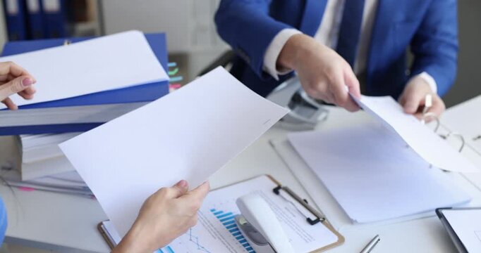 Business partners staple and punch documents during meeting in modern office. Close collaboration while working at paperwork on desk at workspace