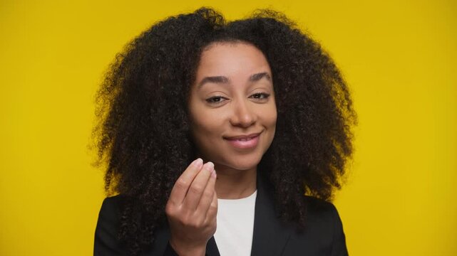 Smirking woman making money gesture on yellow