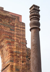 The iron pillar of Delhi, looking up at the top section with stone carving in background