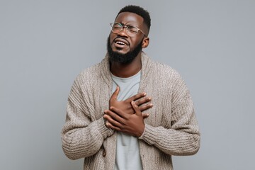 A man in a cardigan sweater appears to be experiencing a heart attack, clutching his chest in pain, isolated against a grey background