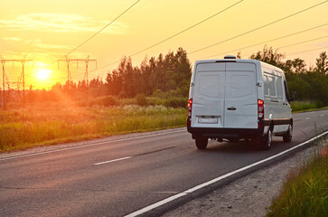 A white truck drives along a highway at sunset.