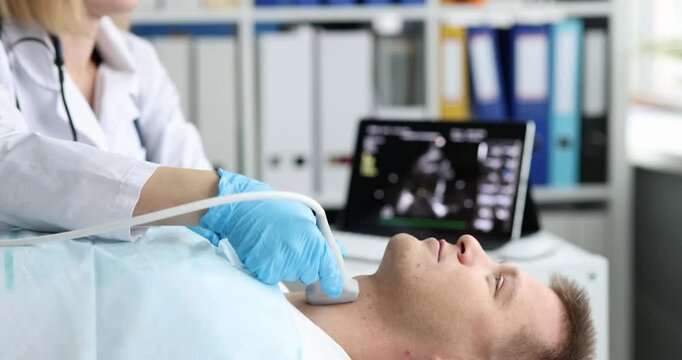 Female doctor uses ultrasound transducer performing examination of male patient thyroid gland in hospital. Medical diagnosis with ultrasound machine