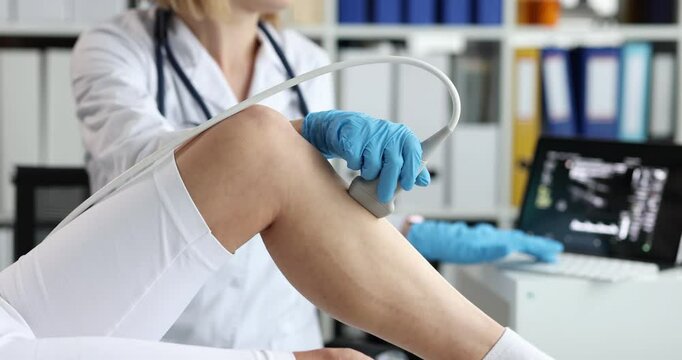 Medical professional in gloves examines lady patient leg using ultrasound transducer. Reviewing diagnostic data on tablet screen in clinical setting