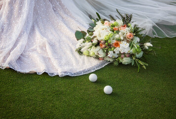 wedding bouquet near of bride dress on the golf field. macro flowers with golf balls near stylish white wedding dress on the green grass. wedding concept, free space