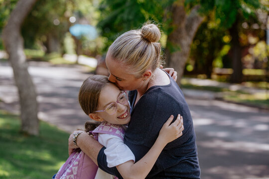 Mother hugging and kissing daughter on the head.