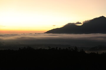 Picturesque view of mountains covered with fog on sunset