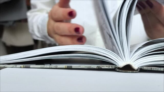 Female hands flip through the pages of a book on the table. Reading literature. The learning process. Education.