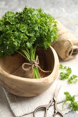 Fresh parsley, thread and scissors on grey textured table, closeup