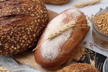 Fresh bread loaves and spikes on white table, flat lay