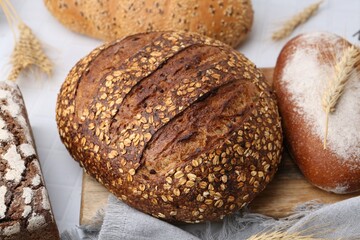 Fresh bread loaves and spikes on white table, closeup