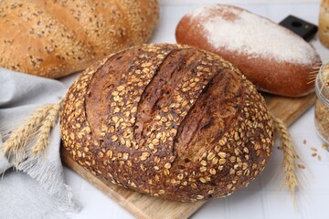 Fresh bread loaves and spikes on white table, closeup