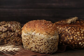 Freshly baked loaves of bread and spikes on wooden table, closeup