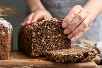 Woman with freshly baked bread at table against grey background, closeup