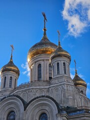 Large building with three domes and a cross on top. The building is white and has gold trim. Church of the Resurrection of Christ and the New Martyrs and Confessors of the Russian Church