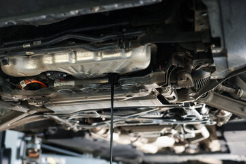 Fototapeta premium Dirty old motor oil dripping from car engine in workshop, closeup