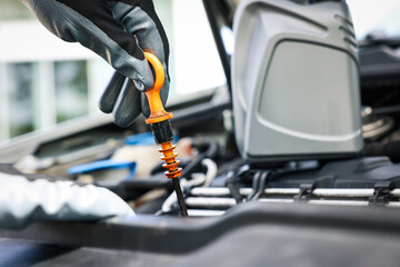 Worker checking motor oil level in car with dipstick, closeup