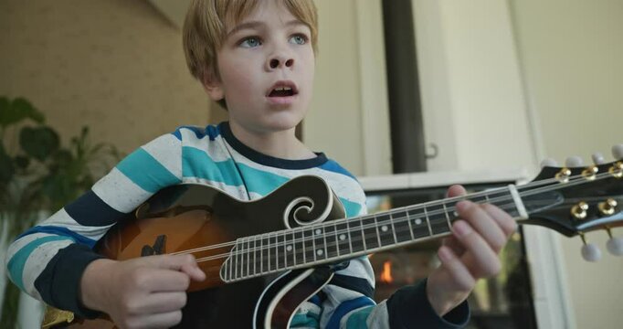 Caucasian Kid Play Mandolin at Home. European Boy Practice Music 4K 10-bit