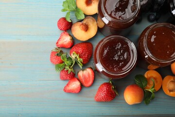 Different jams in jars and ingredients on blue wooden table, flat lay. Space for text