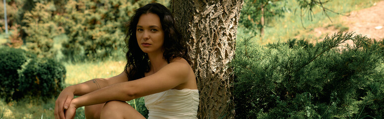 Curly haired young woman enjoying a summer day in a stylish white dress outdoors