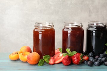 Different jams in jars and ingredients on blue wooden table. Space for text