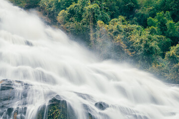 Beautiful waterfall with a lush green forest in the background. The water is flowing down the rocks and creating a beautiful scene. Sustainable waterfall in lush forest promoting water sustainability.