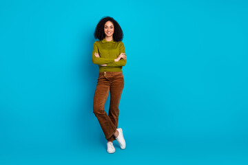 Confident young woman in khaki shirt posing against blue background showcasing casual style and...