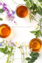 Aromatic herbal tea in glass cups, different flowers and leaves on white wooden table, flat lay....