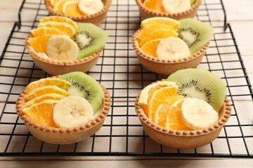 Tartlets with fruits on wooden table, closeup. Delicious dessert