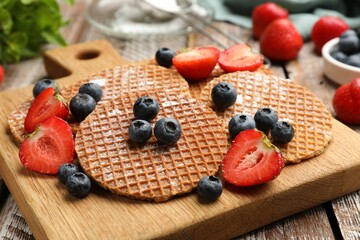 Tasty Dutch waffles (stroopwafels) and berries on wooden table, closeup