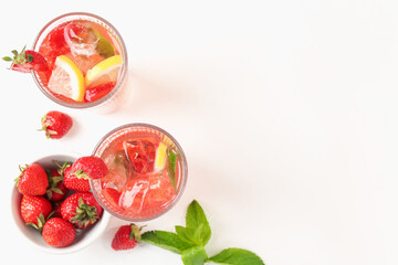 Refreshing drink with strawberries, mint, lemon and ice on white table, flat lay. Space for text