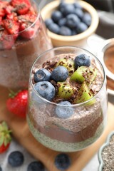 Delicious chocolate pudding with chia seeds, kiwi and blueberries in glass on grey table, closeup