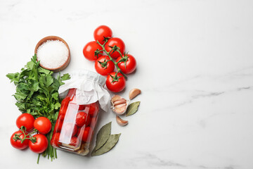 Tasty pickled tomatoes in jar and ingredients on white marble table, flat lay. Space for text
