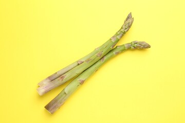 Fresh ripe raw asparagus on yellow background, top view
