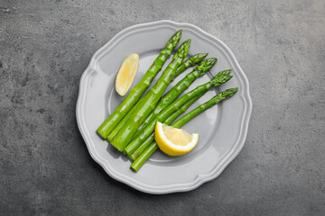 Tasty cooked asparagus served with lemon on grey table, top view