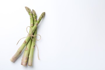 Fresh ripe raw asparagus on white background, top view. Space for text