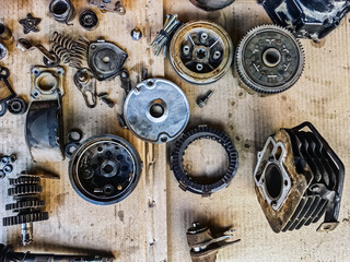 Old parts of motorcycles background. Repair and maintenance old parts of engine. Old motorcycle spare parts on corrugated paper background. Disassembly of spare parts, gear, differential, engine, old.
