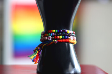 Hand figurine with colorful rainbow bracelets and heart shaped ring. Pride flag in the background....