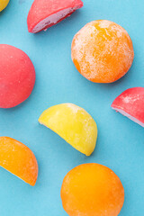 Vertical photo of colorful mochi desserts with various fruit and cream fillings on pastel blue background. Perfect for mobile content, packaging, or food design