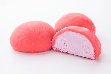 Close-up of pink mochi desserts with creamy violet filling on clean white background. Japanese...