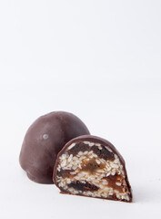 Gourmet chocolate candy filled with a mix of sesame seeds, dates, and nuts. Cut open to reveal textured filling. Isolated on white background. Ideal for healthy dessert branding