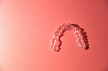 Close up of invisible aligners on pink background with copy space. Plastic braces dental retainers...